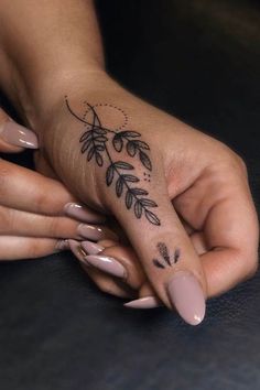 a woman's hand with a tattoo on her left thumb and fingers, holding the other