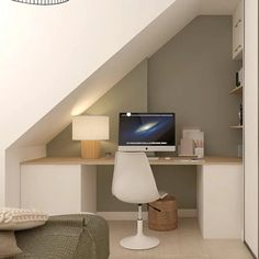 a desk with a computer on it under a slanted ceiling