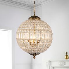 a chandelier hanging from the ceiling in a room with white walls and fireplace