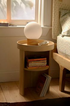 a lamp sitting on top of a wooden table next to a book shelf filled with books