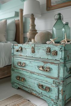 an old blue dresser with sea shells on top and starfish in the bottom drawer