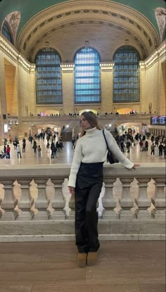 a woman standing in the middle of a train station with her hands on her hips