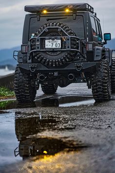 a black jeep driving down a wet road with its lights on and the number 80 on