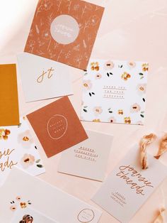 several different types of greeting cards on a white surface with flowers and leaves around them