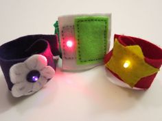 three felt bracelets with lights on them sitting next to each other in front of a white background