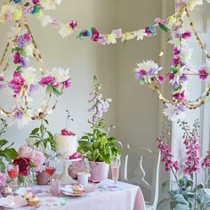 the table is set with pink and white flowers in vases, plates and cups