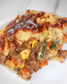 a piece of meatloaf on a white plate with sauce and vegetables in it