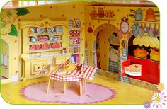 a doll house with a table and chairs in front of the kitchen area is shown