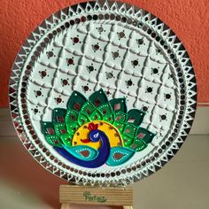 a decorative glass plate sitting on top of a wooden stand in front of a red wall