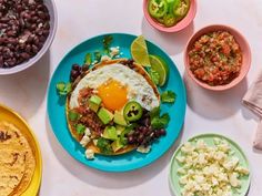 an assortment of food is displayed on three different plates, including eggs and black beans