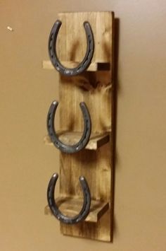 two horseshoes are mounted to a wooden wall with hooks on the bottom and sides