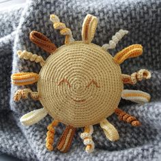 a knitted sun on top of a gray blanket