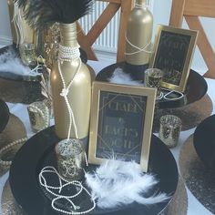 a table topped with gold vases and black plates covered in pearls, feathers and other decorative items