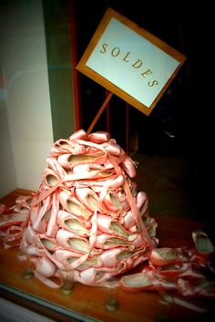 a pile of ballet shoes sitting on top of a wooden table next to a sign