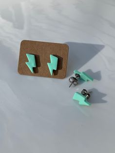 two pairs of green earrings sitting on top of a white table next to each other