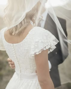 a bride and groom standing under a veil