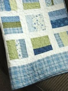 a blue and green patchwork quilt sitting on top of a couch next to a pillow