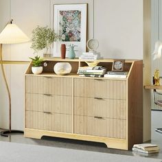 a living room with a lamp, dresser and pictures on the wall