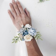 a person's hand wearing a bracelet with blue and white flowers on the wrist