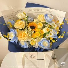 a bouquet of flowers sitting on top of a white table next to a blue box