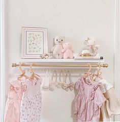 there is a shelf with baby clothes on it and two teddy bears next to them