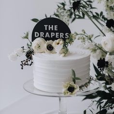 a white cake topped with flowers and the words the drapers on top of it