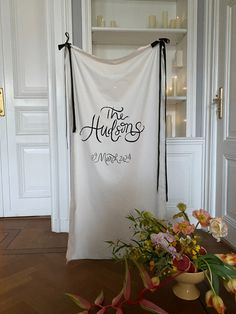 a white bag sitting on top of a hard wood floor next to vases filled with flowers