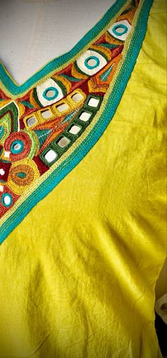 a yellow top with colorful designs on it