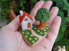 a hand holding a tiny house and tree