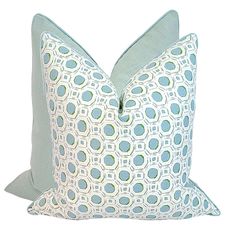 a blue and white pillow sitting on top of a bed next to a green pillow