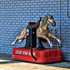 a statue of a horse on top of a red box next to a brick wall