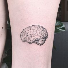 a small black and white tattoo of a brain on the right side of the leg