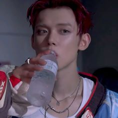 a man with red hair drinking from a water bottle