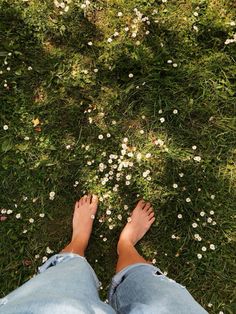 a person standing in the grass with their feet up and flowers growing all over them