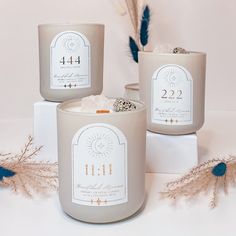 three candles sitting next to each other on top of a white box with feathers around it