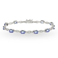 This gorgeous tennis bracelet displays glistening oval-cut 6x4mm tanzanite gemstones that are set in between a polished and white topaz studded swirl design. The bracelet is created of 925 sterling silver and is tarnish resistant plus nickel free. It secures with a box and tongue with a safety latch. Look and feel glamorous with this luxurious piece of jewelry! Product Details Metal Type sterling-silver Metal Stamp 925-sterling Weight 8.5GR Length 7.25IN Width 4.85MM Clasp Type box-with-tongue-a Indian Diamond Jewellery, Basic Bracelet, Anklet Designs, Bracelet Display, Jewelry Bracelets Silver, Birthstone Bracelets, 925 Silver Jewelry, Ankle Bracelets, Tennis Bracelet