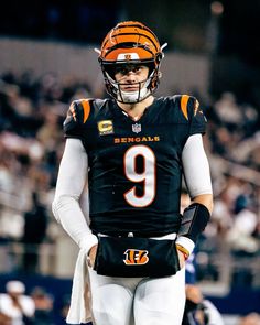 a football player is standing on the field with his hands in his pockets and wearing a helmet