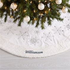 a white christmas tree skirt with snowflakes and ornaments on it, hanging from the ceiling