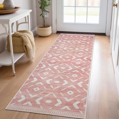 a pink and white rug on the floor in front of a door with a potted plant