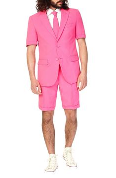 This bright pink two-piece short suit ditches the pants and long-sleeves to go against the grain of boring, formal style with fresh, bold personality. Tailored for a modern fit, it includes a two-button short-sleeve suit jacket and shorts cleanly styled with tonal buttons and stitching, as well as a matching tie to pull the whole outfit together. Jacket has a two-button closure; notch lapels; cuffed short sleeves; chest pocket; front flap pockets; side vents. Shorts have a zip fly with button-ta Smart Casual Wardrobe, Derby Outfits, Color Outfits, Solid Color Outfits, Pink Two Piece, Party Suits, Pink Suit, Men’s Suits, Summer Suits