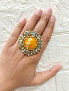 a woman's hand holding a yellow and white ring with the letter b on it