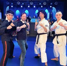 three men in black shirts and white pants posing for the camera with their hands together