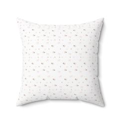 a white pillow with small pink flowers on the front and back of it, against a white background