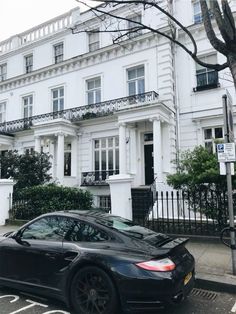 a black car parked in front of a white building on the side of a street