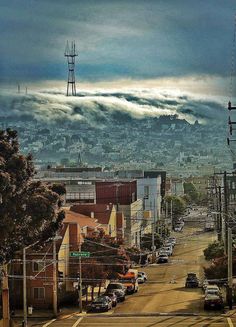 a city street filled with lots of traffic under a cloudy sky over a mountain range