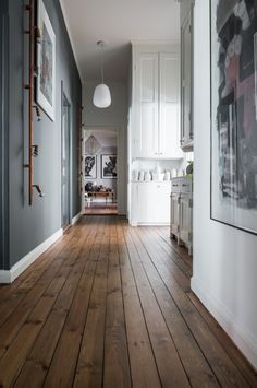 an empty hallway with wood floors and white cabinets on either side of the room is a kitchen