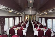 a dining car on a train with red and white tablecloths, silverware and wine glasses