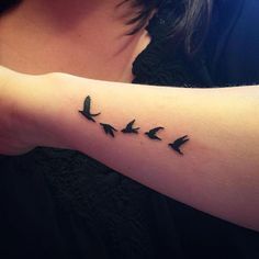 a woman with a tattoo on her arm that has birds flying in the same direction