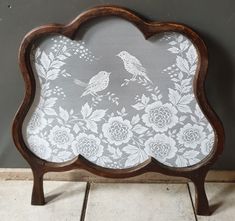 a wooden frame with white flowers and birds on it