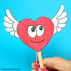 a hand holding up a paper heart with wings